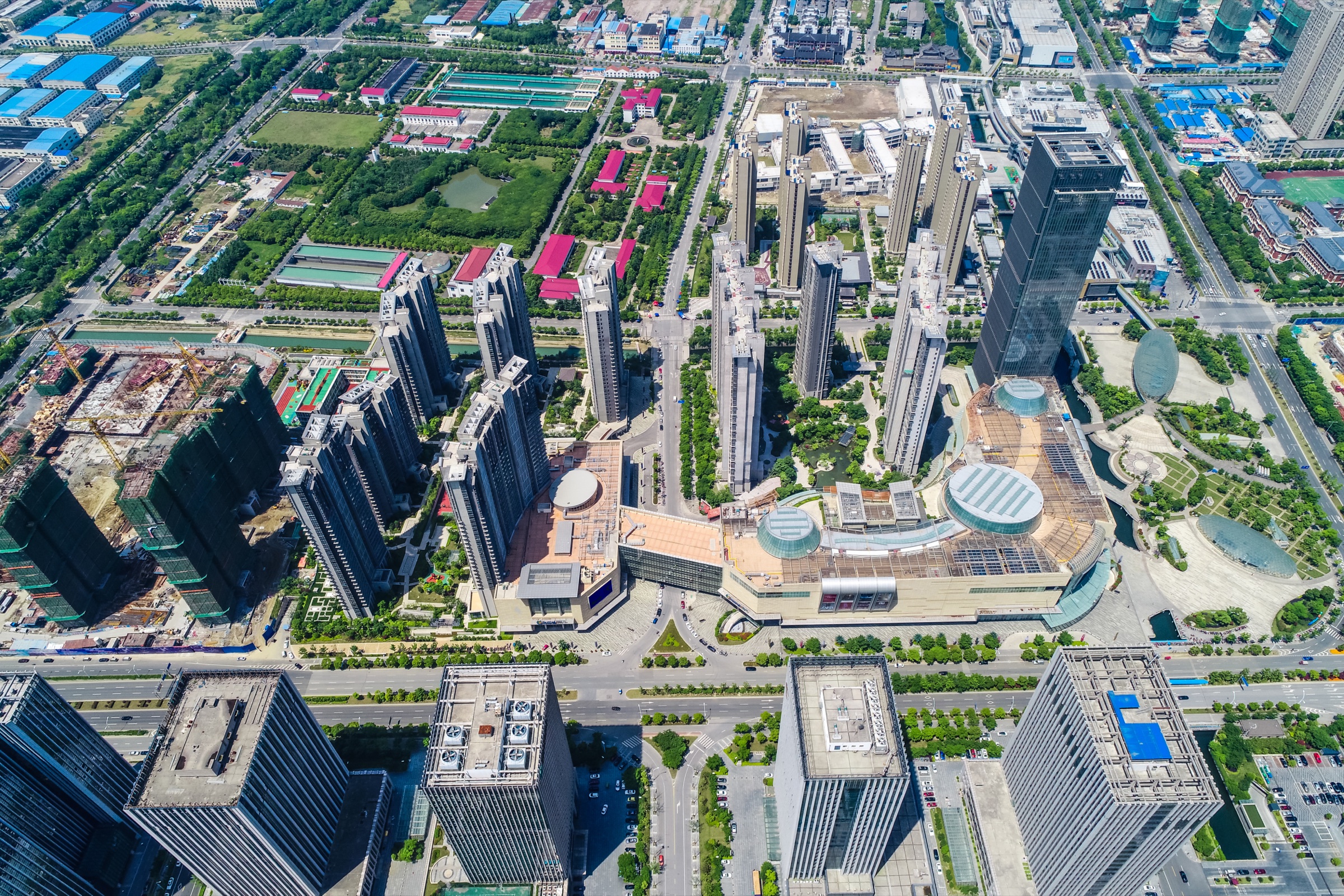 Aerial view of high-rise towers, a shopping complex and green parks in a large city.