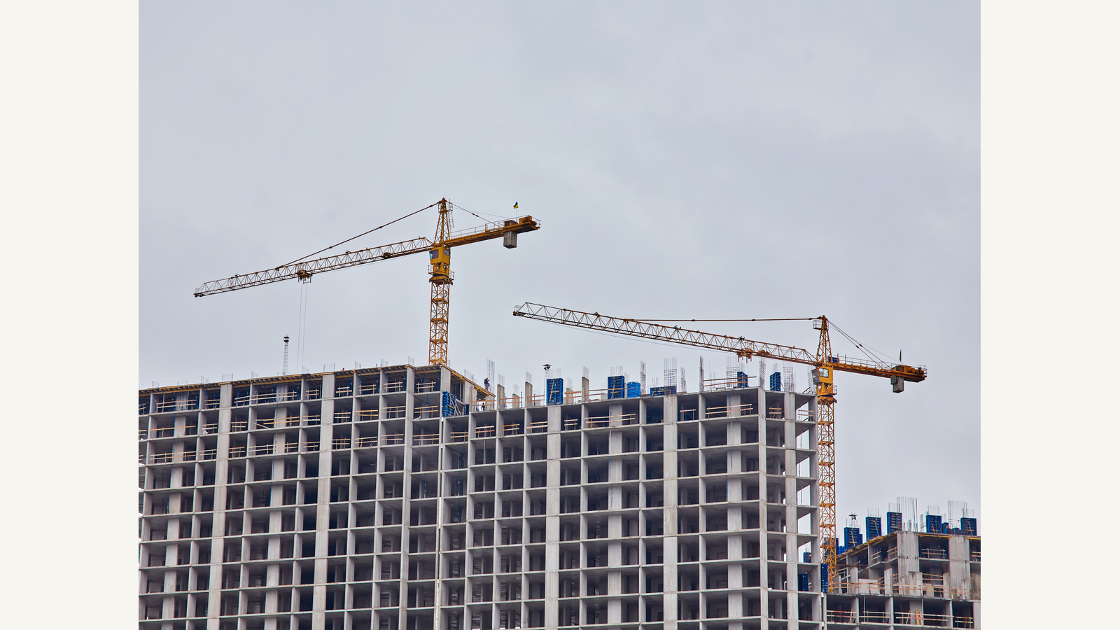 Illustration of cranes rising above a construction site with unfinished building structures against an open sky.