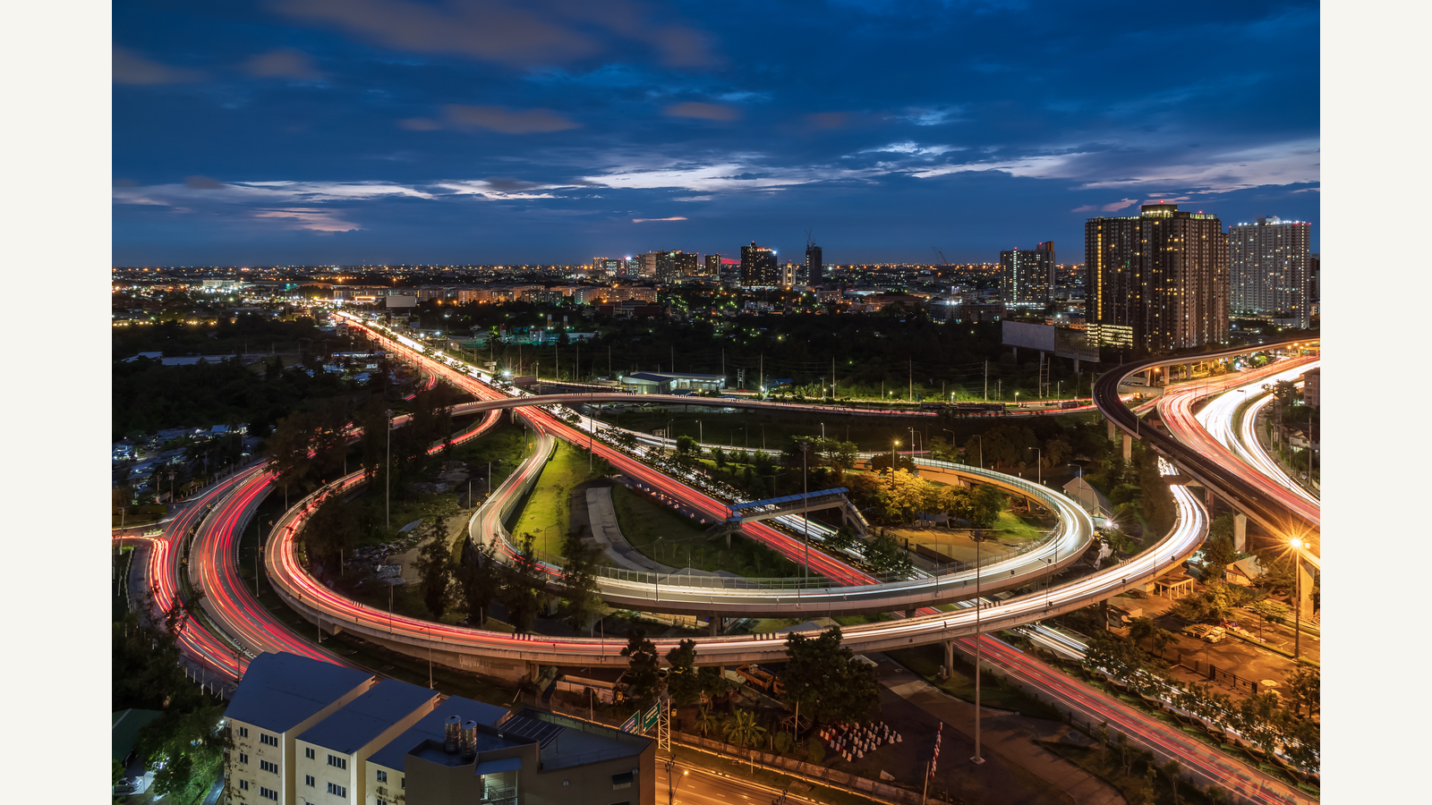 Illustration of an elevated road interchange and expressway under a twilight sky in an urban setting.